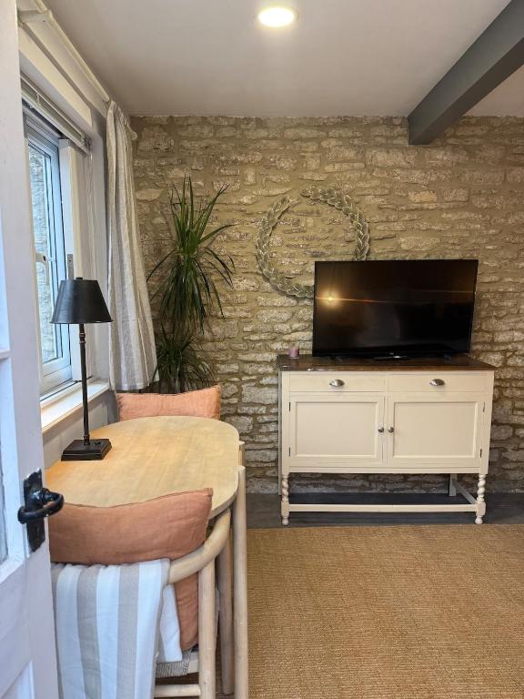 a living room with a table and a television at The Grain store in Cirencester