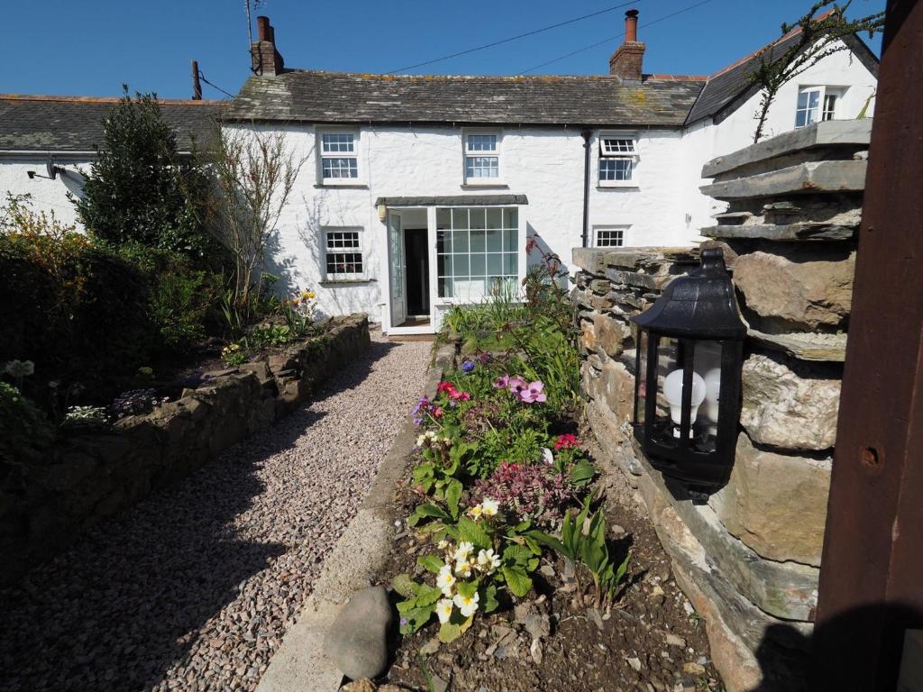 a white house with a stone wall and flowers at Trewetha Cottage Bed & Breakfast in Port Isaac