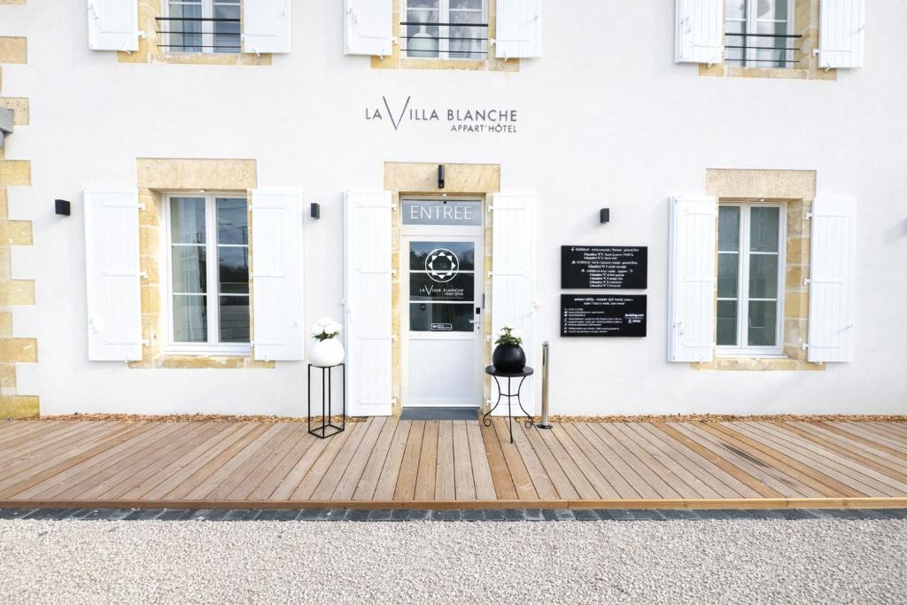 a front door of a white building with two chairs in front at La Villa Blanche Appart hôtel in Salles