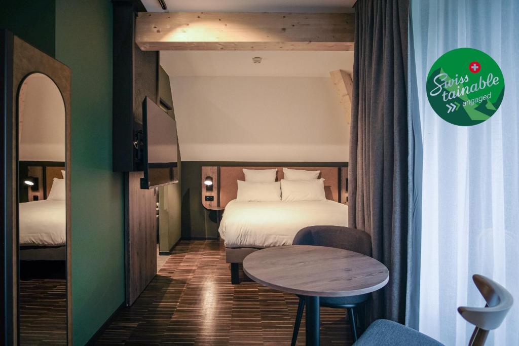a hotel room with a bed and a table at Hota Hotel Saint-Imier in Saint-Imier