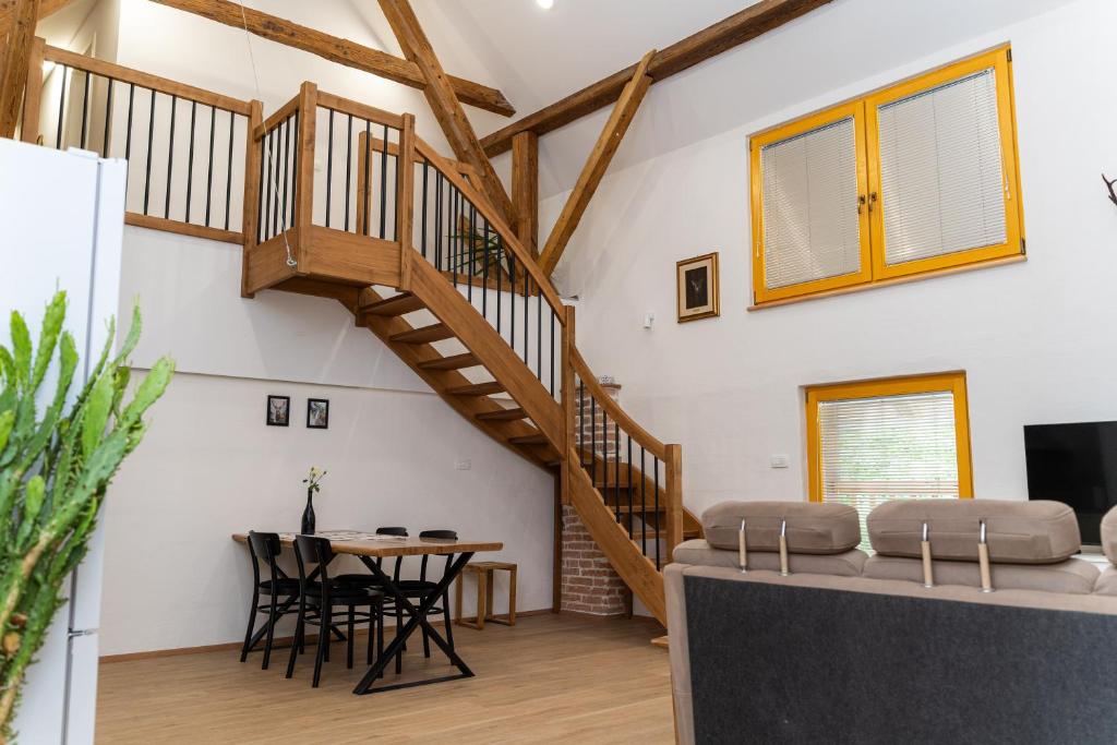 a living room with a wooden staircase and a table at Timeless Barn in Ljubljana