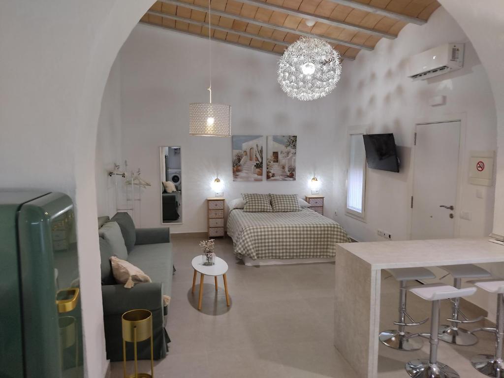 a living room with a bed and a kitchen with a table at La corrala de la calle Sol in Jerez de la Frontera