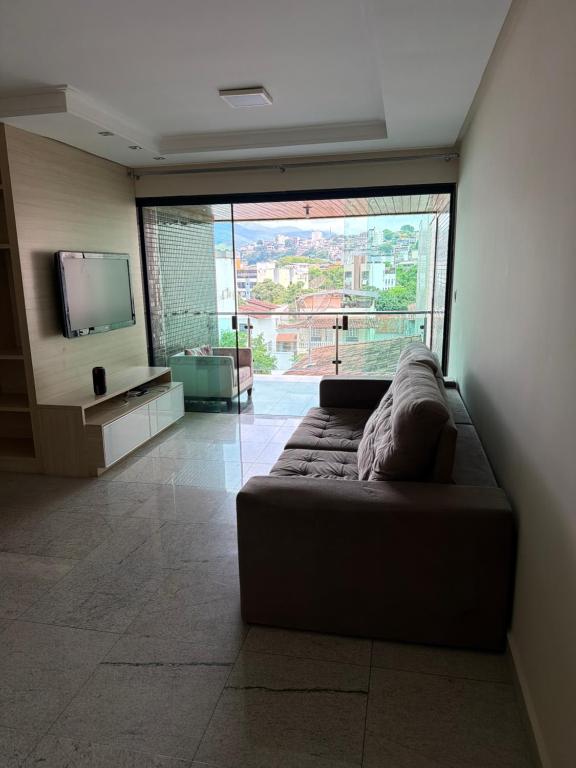 a living room with a couch and a large window at Tr hospedagem in Ipatinga