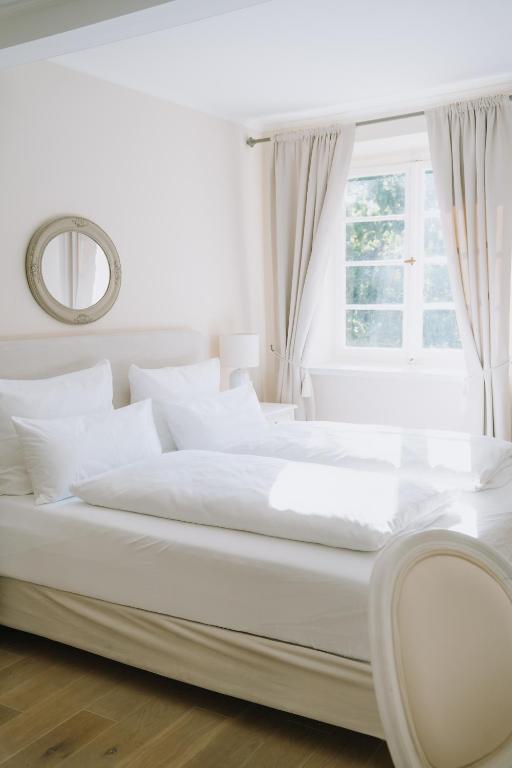 a white bed with white pillows and a window at KAROLINGERHOF - Mosel in Kröv