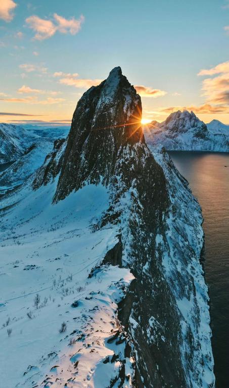 a mountain in the snow with the sun setting behind it at Rigmorhuset in Fjordgård