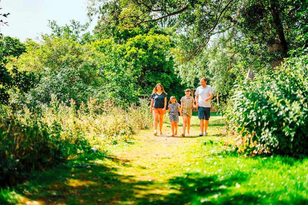 a family walking down a dirt path in the woods at Riverside Essential Clover Caravan Pet 1 in Wooler