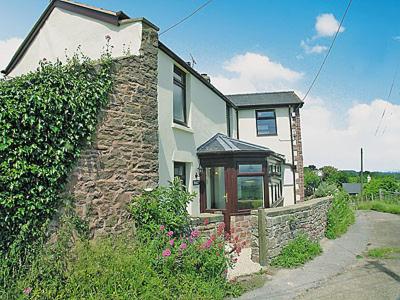 a house with a stone wall next to at Vale View Cottage in Cinderford