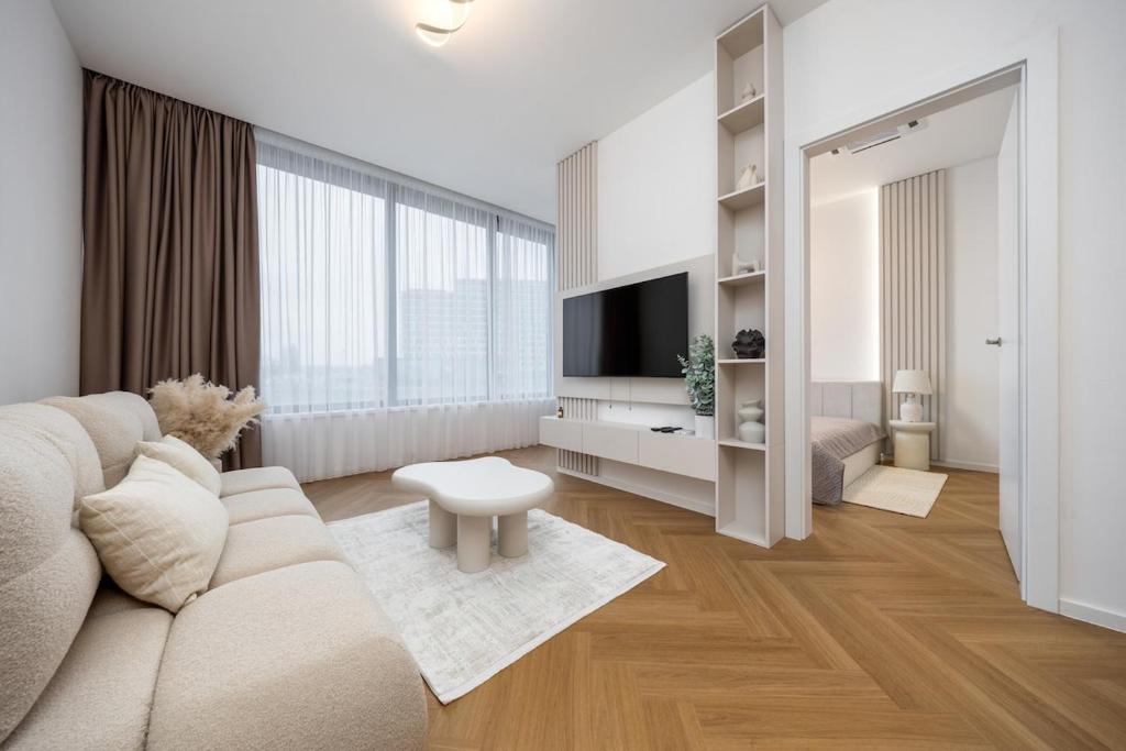 a white living room with a couch and a tv at Apollo One, 1BR Signature Residence in Nivy