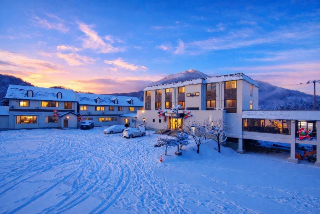 a building in the snow with a sunset at Hotel Sol at Lake Toya in Lake Toya