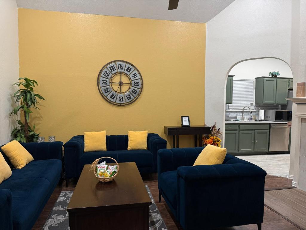 a living room with blue couches and a clock on a yellow wall at Historic Downtown McKinney 3BR in McKinney