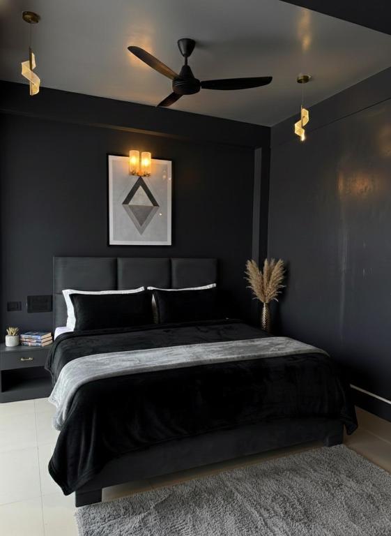 a black bedroom with a bed and a ceiling fan at Noir Suites in Patna
