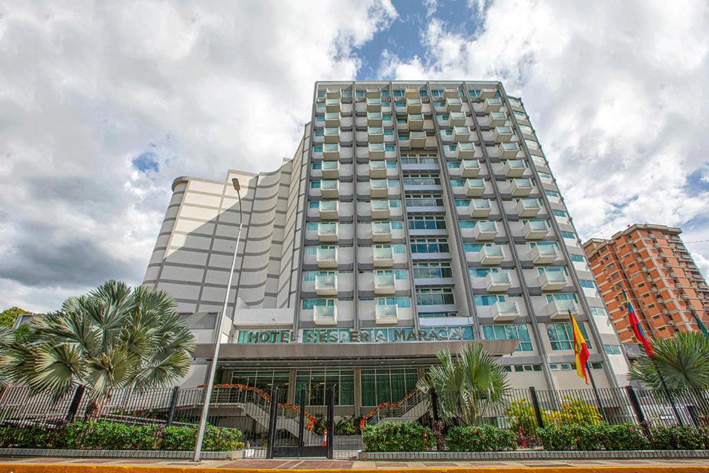 a large building with palm trees in front of it at Hesperia Maracay in Maracay