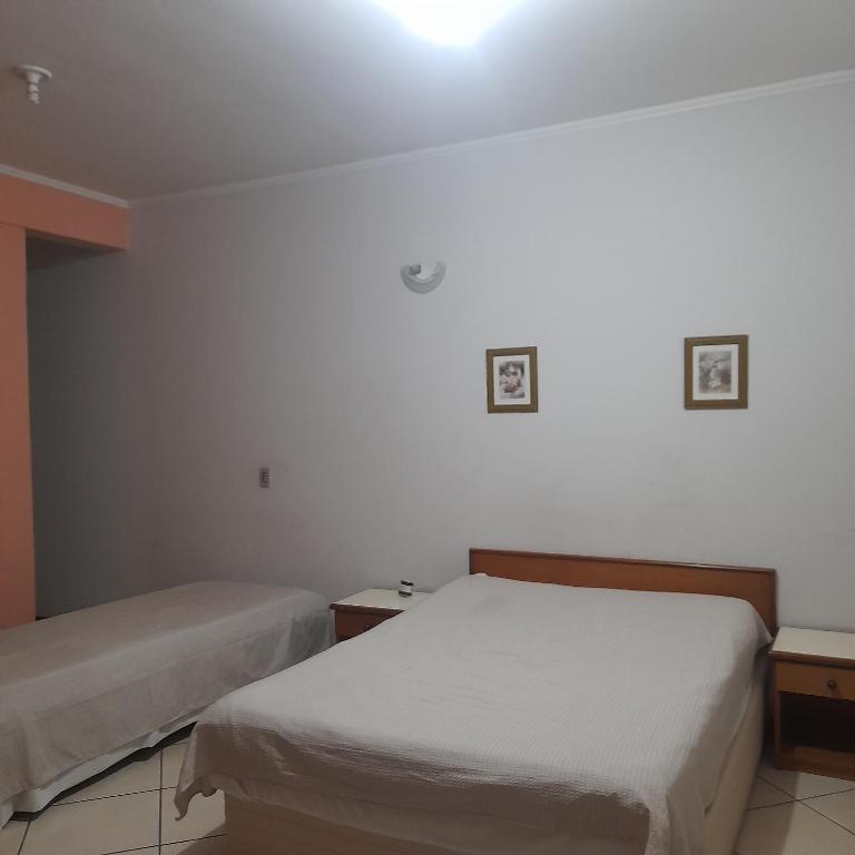 a bedroom with two beds and a light on the wall at Village Hotel in São Borja