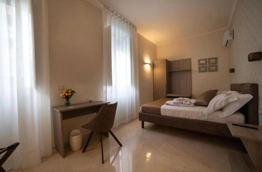 a bedroom with a bed and a desk and a window at Bebio Rooms in Trani