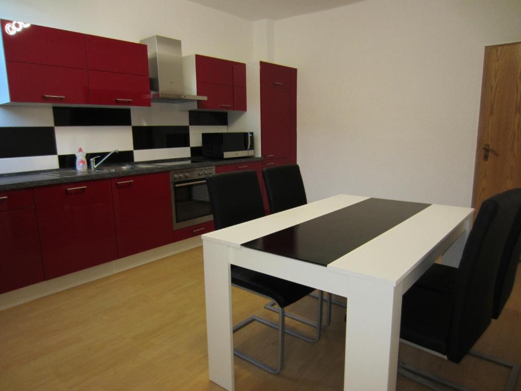 eine Küche mit roten Schränken sowie einem weißen Tisch und Stühlen in der Unterkunft Monteur Apartment Charlotte in Hagen