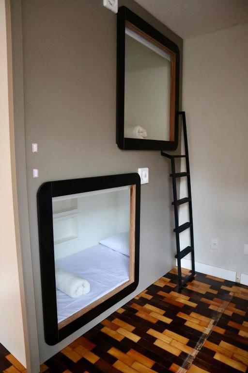 a mirror on a wall with a bed in a room at Nihon Cápsula Hotel in Florianópolis