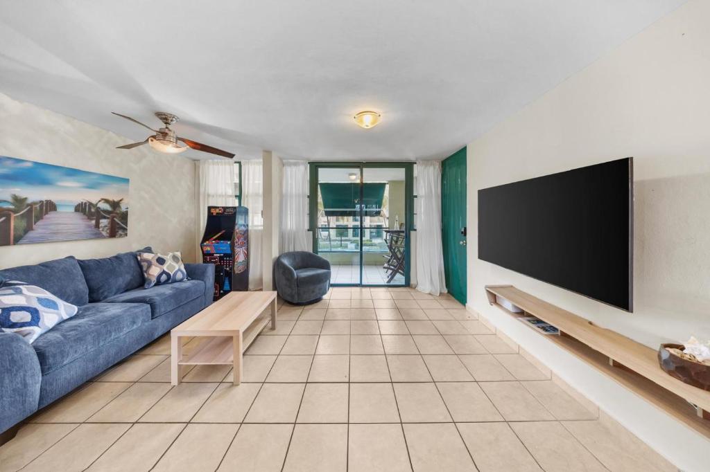 a living room with a blue couch and a flat screen tv at Beachfront Aquatika Resort- Style-Pools & Ocean in Rio Grande