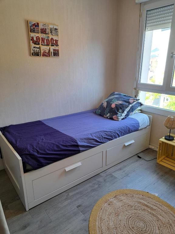 a bedroom with a bed with purple sheets and a window at Petite Chambre CHEZ MARINA in Chantepie