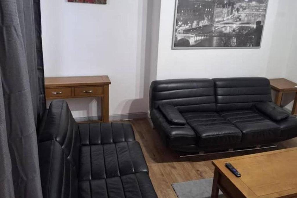 a black leather couch and a chair in a living room at 3 Bed House Sleeps 5 - Free Parking - Tv & WiFi in Sheffield