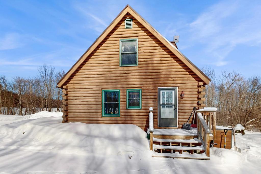 a log cabin with a porch in the snow at North Hill Cabin in Jay