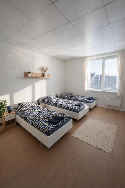 three beds sitting in a room with a window at Apartmány Škodova Přerov in Přerov