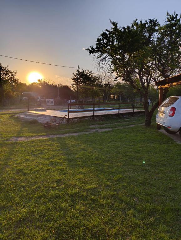a car parked in a field with the sunset in the background at Cabañas EL VALLE in Villa Rumipal