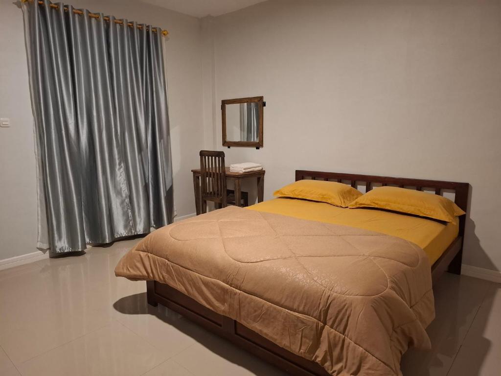 a bedroom with a bed with yellow sheets and a mirror at Waceno Umma in Ruteng