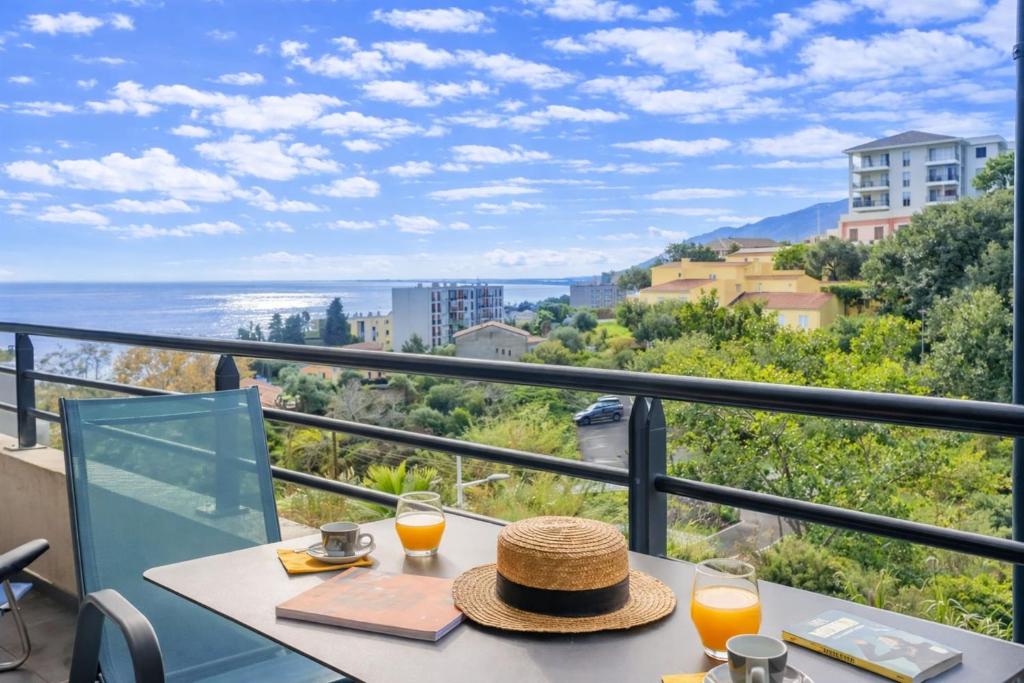 a table with a hat on a balcony with a view of the ocean at Casa Pouty Beach in Bastia