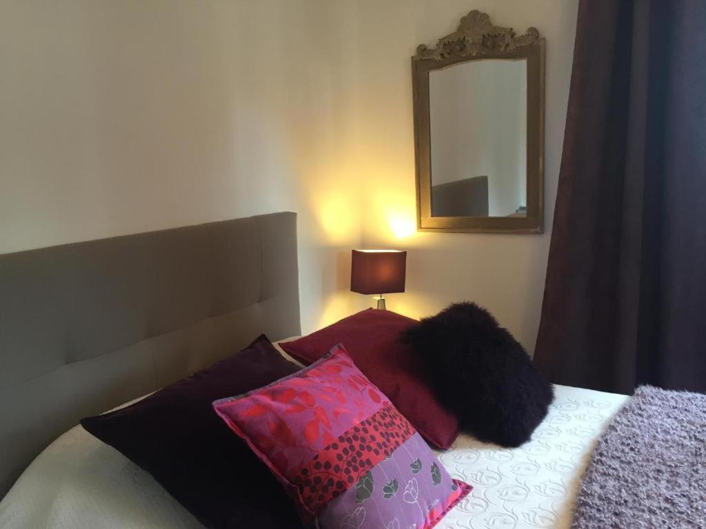 a bedroom with a bed with pillows and a mirror at Studio Girofle dans Maison d'hôtes L'écrin des Saveurs in Schwenheim
