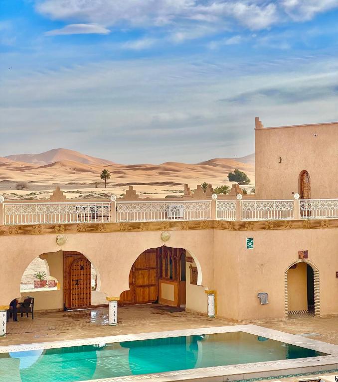 a resort with a swimming pool in the desert at Hotel Sunset Palace in Merzouga
