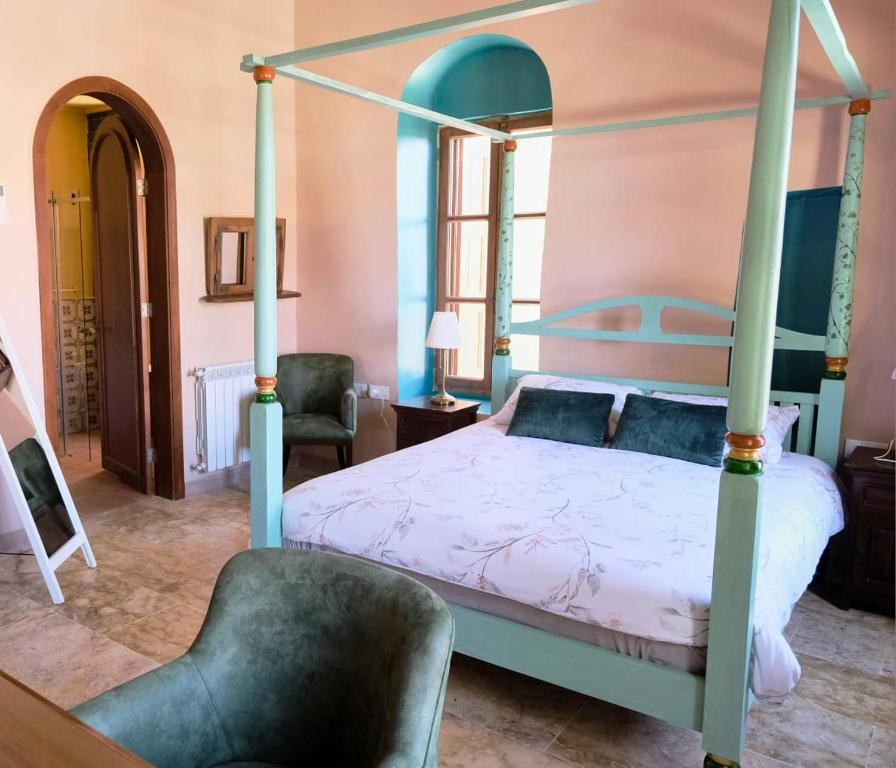 a bedroom with a four poster bed and a chair at Spiritu in Ḩārat al Qal‘ah
