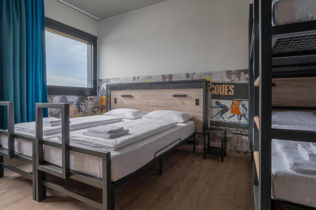 a bedroom with two bunk beds and a window at a&o Hostel Milano Ca Granda in Milan