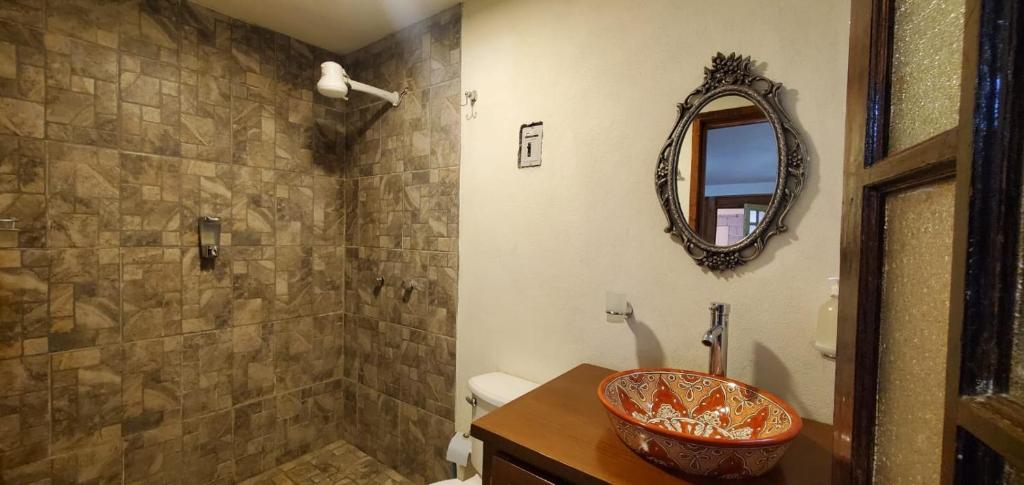 a bathroom with a sink and a shower with a mirror at Zirahuén 6 personas in Zirahuén