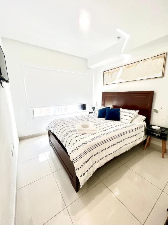 a white bedroom with a large bed with blue pillows at Studio Apartment with backyard - All Private! in Homestead