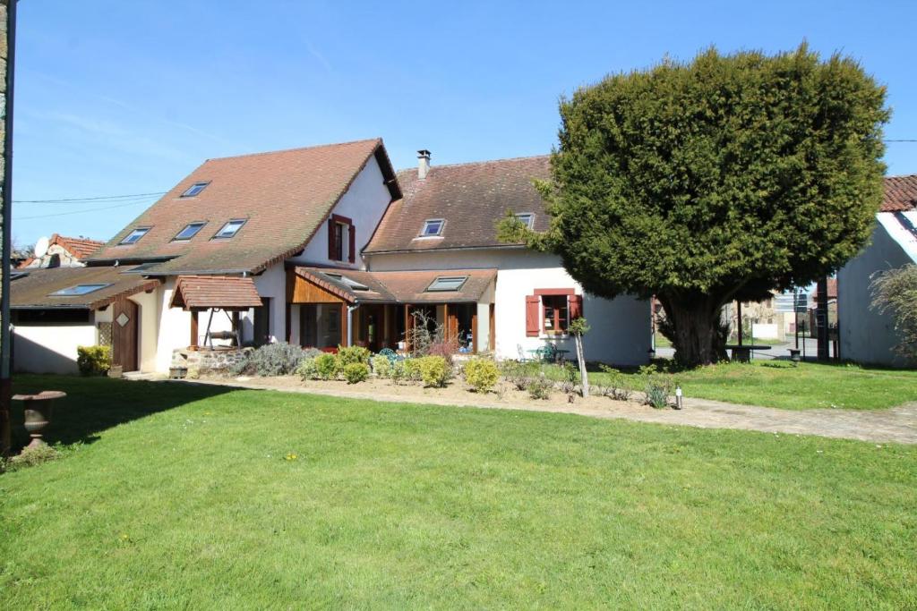 a house with a tree in front of a yard at Les tuilières in Masléon