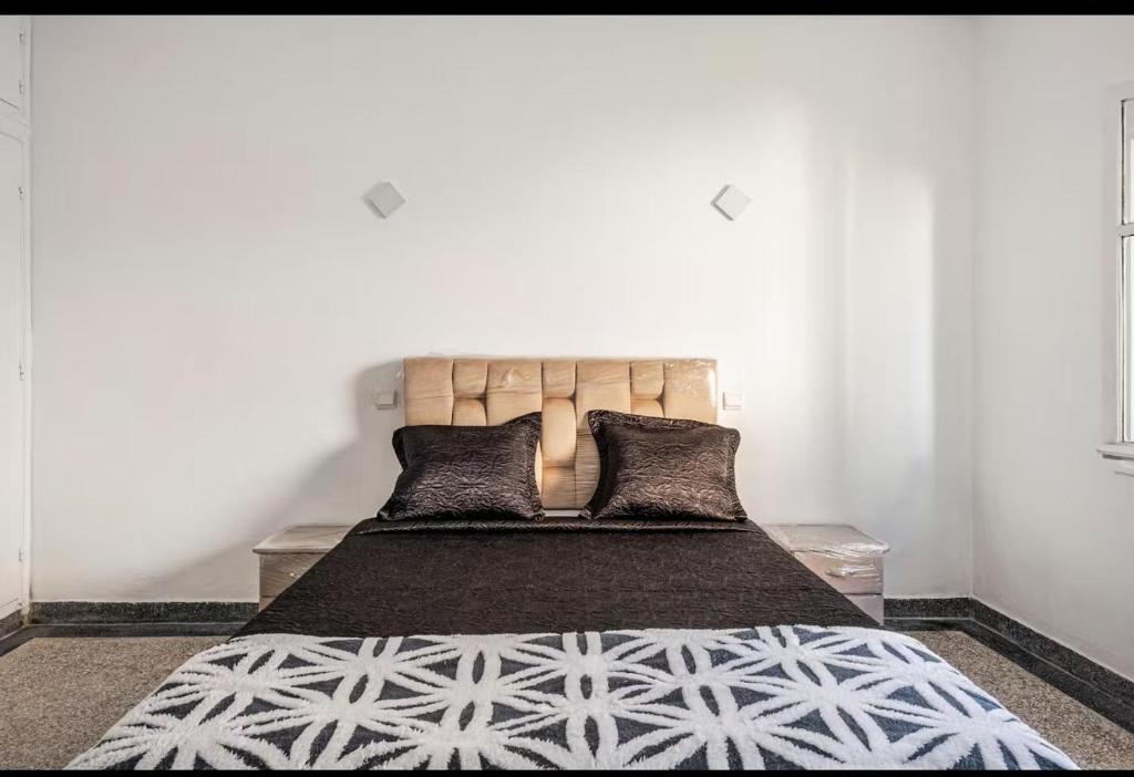a bedroom with a large bed with black and white sheets at Villa à harhora in Temara