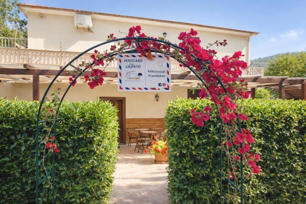 a garden arch with red flowers in front of a house at Villa Corocael in Castellabate