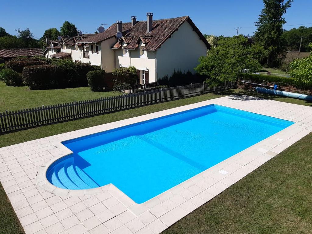 a large blue swimming pool in front of a house at Reves au Soleil in Thiviers