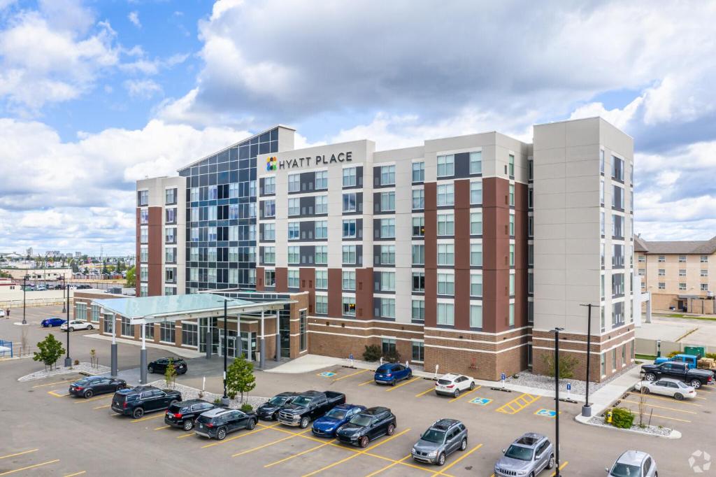 a large building with cars parked in a parking lot at Hyatt Place Edmonton West in Edmonton