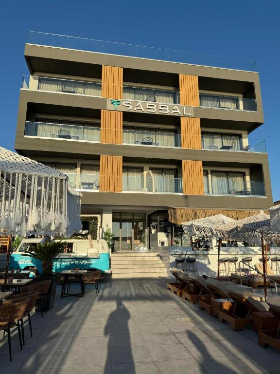 a large building with tables and umbrellas in front of it at SABBAL apartments in Salamina