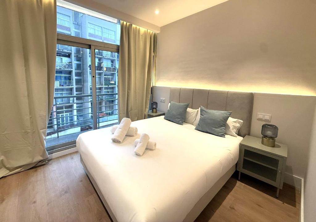 a bedroom with a large white bed with towels on it at Madrid Modern Studio with Terrace & Parking in Madrid