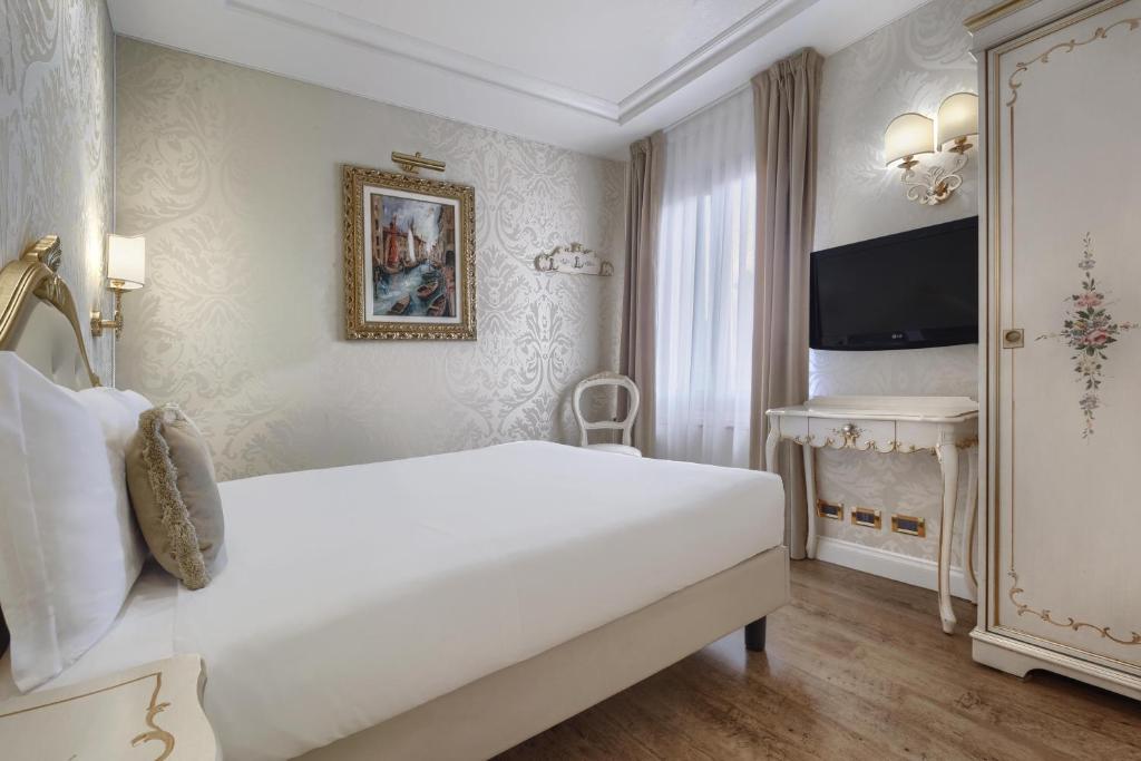 ein Schlafzimmer mit einem großen weißen Bett und einem Fernseher in der Unterkunft Hotel Olimpia Venice, BW Signature Collection 3sup in Venedig