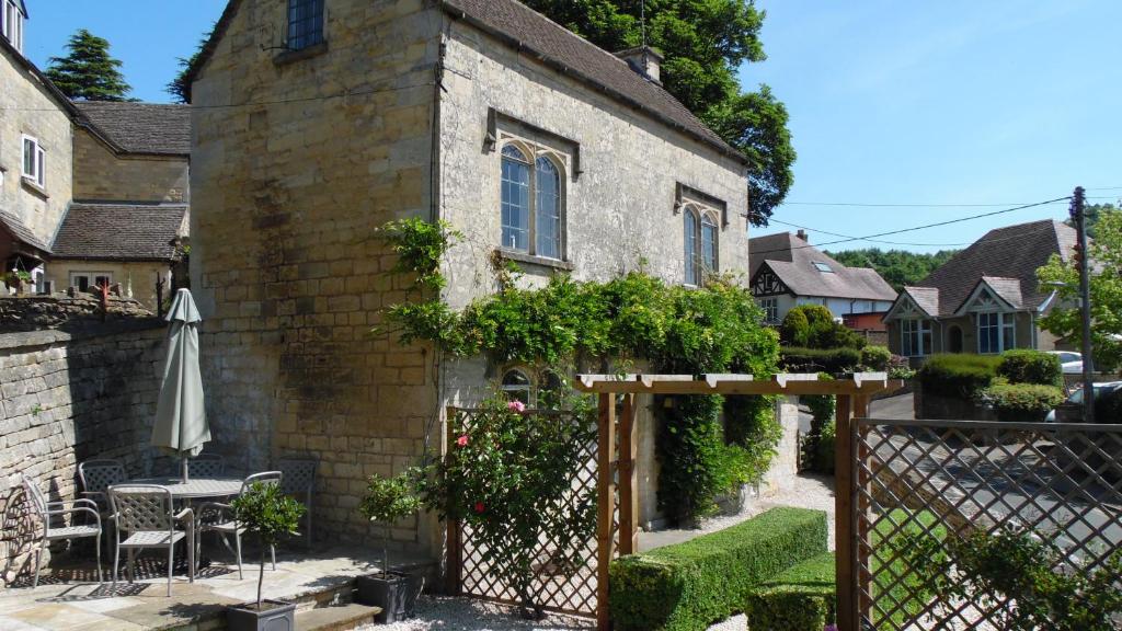 an old brick house with a table and an umbrella at Rose Cottage, Rodborough in Stroud