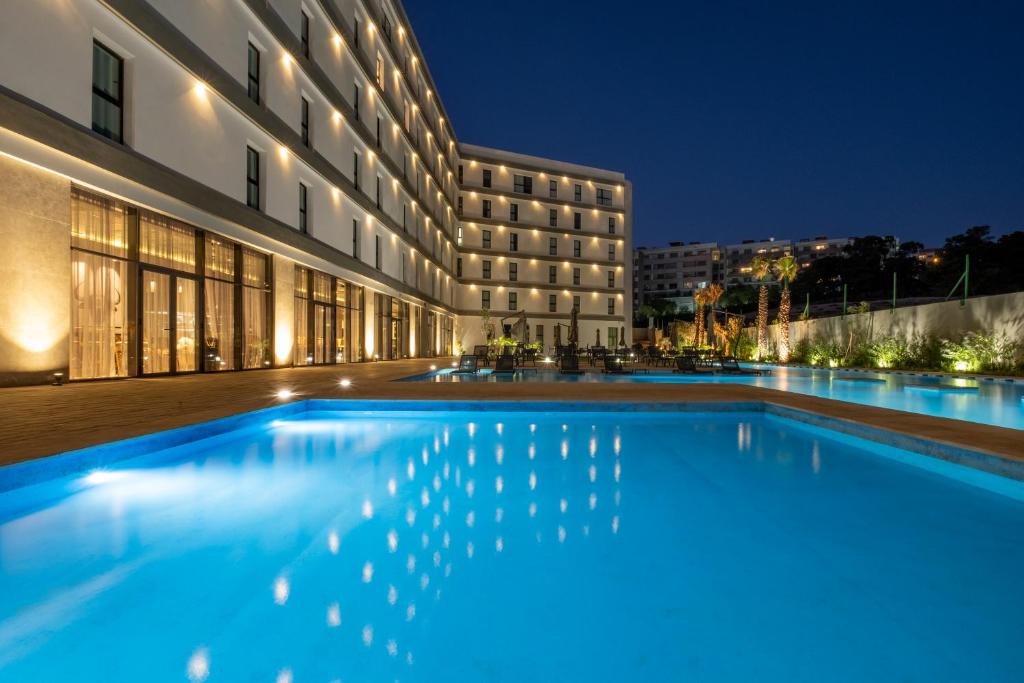 a swimming pool in front of a building at night at Occidental Tanger in Tangier
