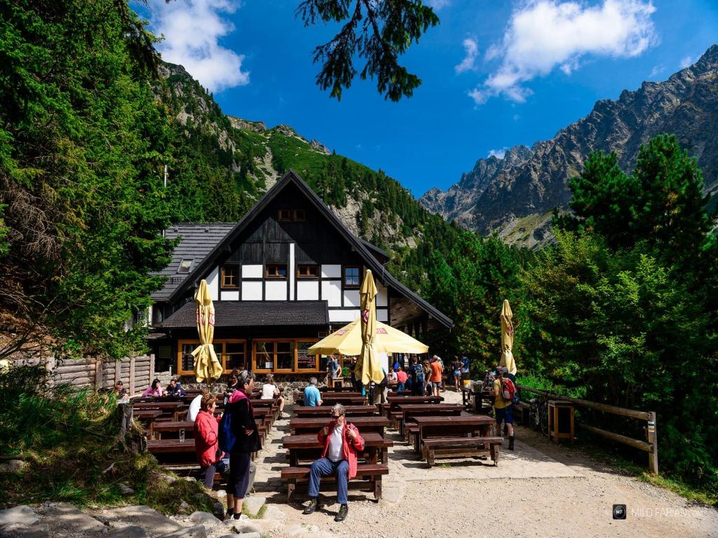 people standing around a wooden bench in a wooded area at Majláthova Chata Popradské Pleso in Štrbské Pleso