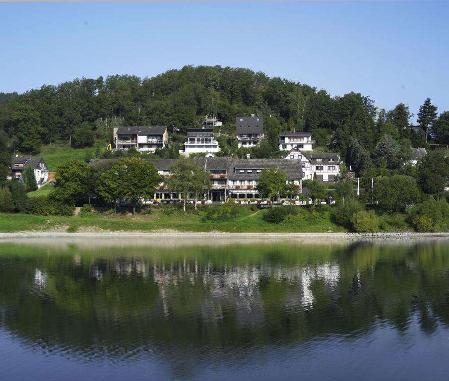 eine Gruppe von Häusern auf einem Hügel neben einem See in der Unterkunft Hotel Paulushof in Simmerath