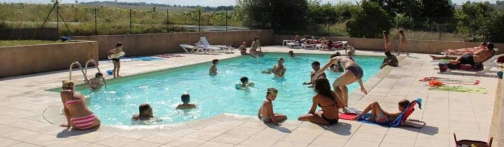 a group of people in a swimming pool at ZEcamping 3 dog friendly avec piscine au bord du lac de la Thésauque in Nailloux