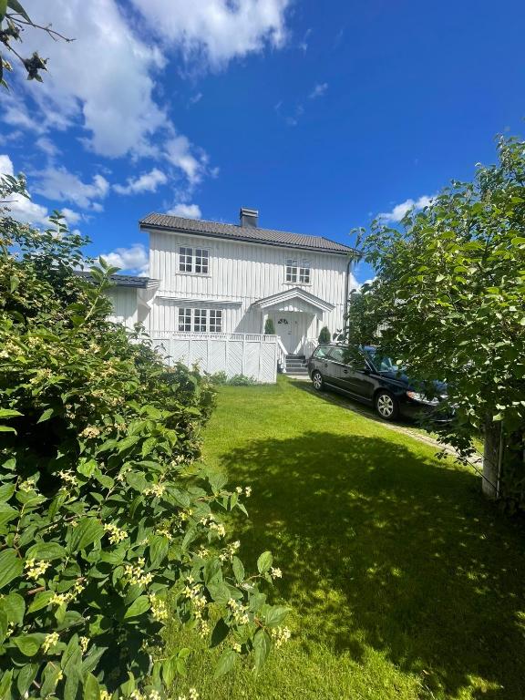 a car parked in front of a white house at Familievennlig fritidsbolig i hjertet av Flå, perfekt for besøk i Bjørneparken in Flå