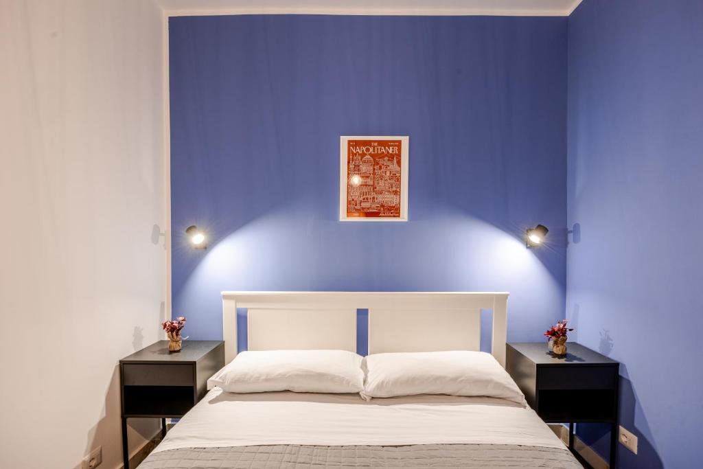 a blue bedroom with a white bed and two night stands at Nalusa - al centro della riviera di chiaia in Naples