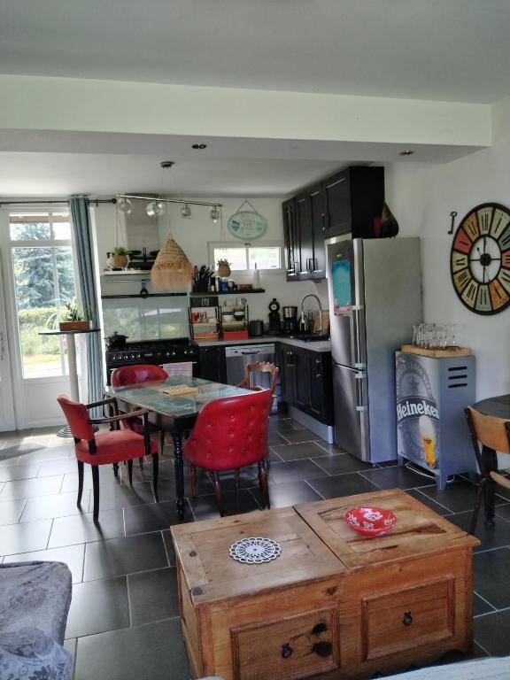 a kitchen with a table and a refrigerator at Murmure de Tilleul in Alembon